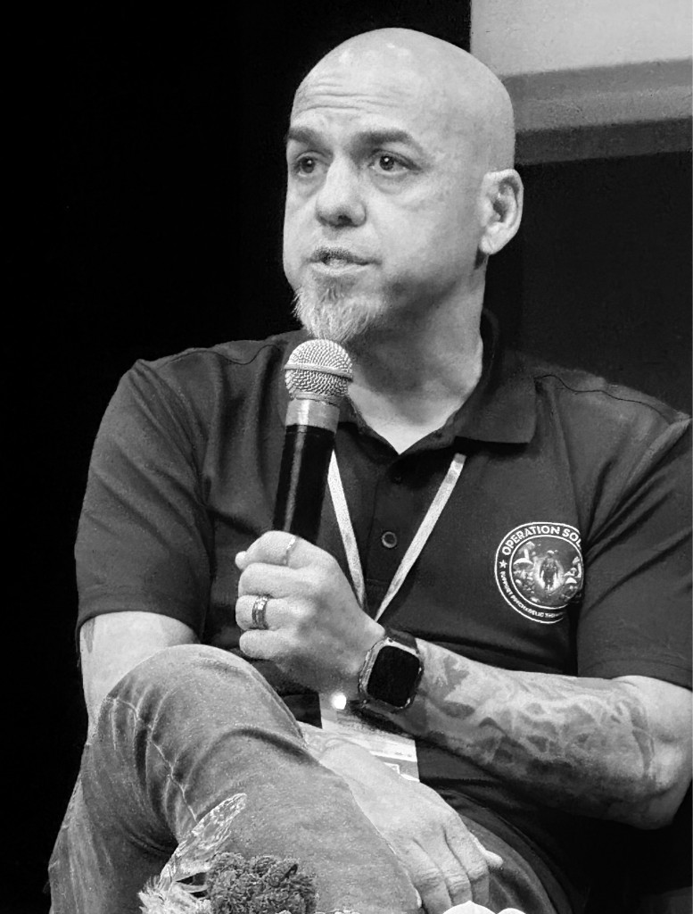Gabriel Gonzales speaking while wearing an Operation Solace polo.