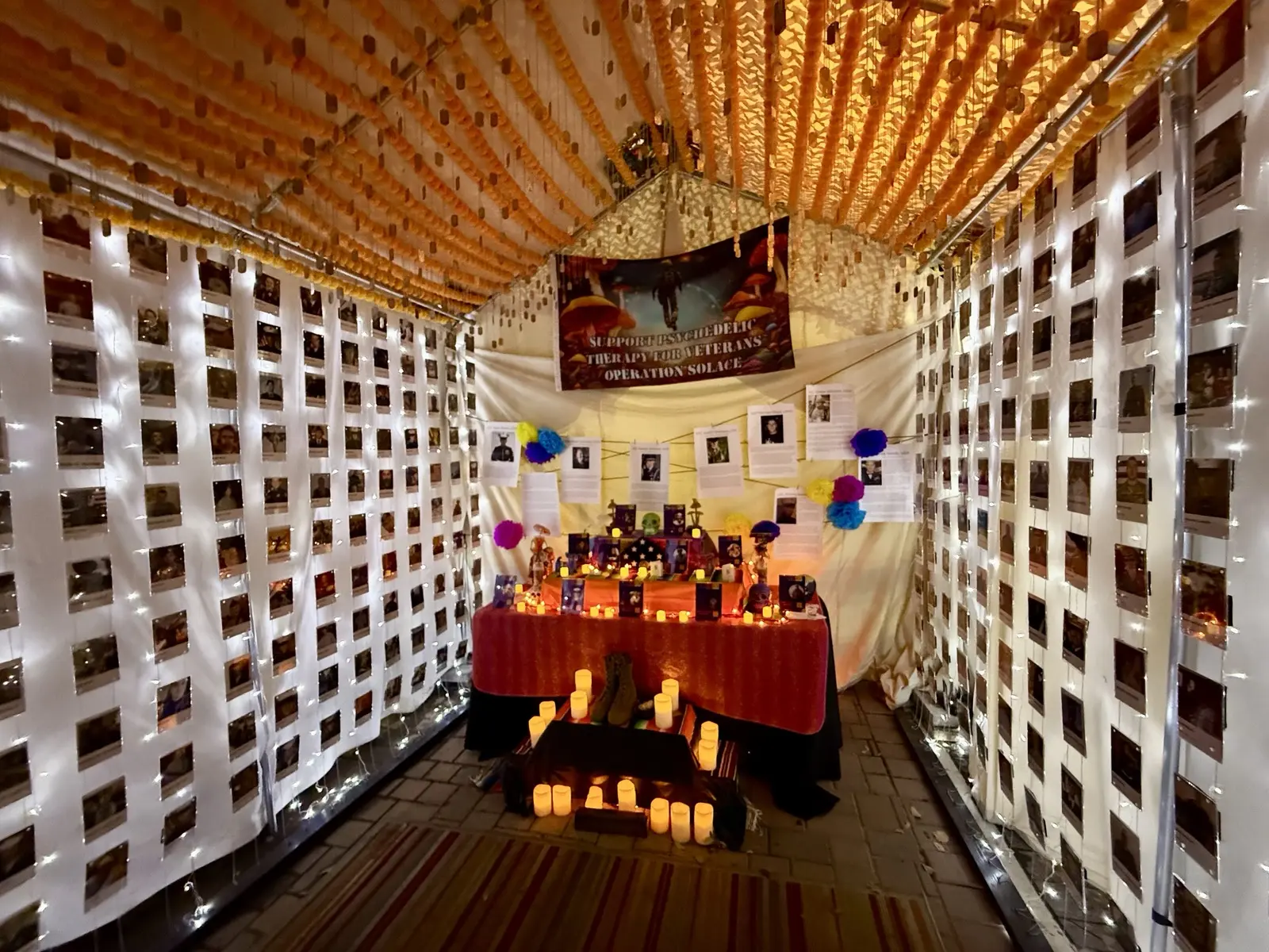 The Operation Solace memorial altar installation, lit with candles and string lights at night.